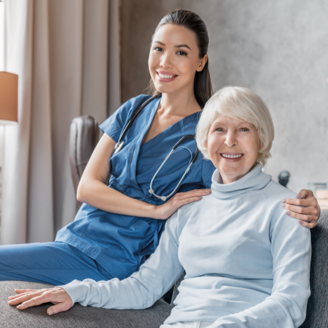 Nurse sitting with arm around an elderly woman